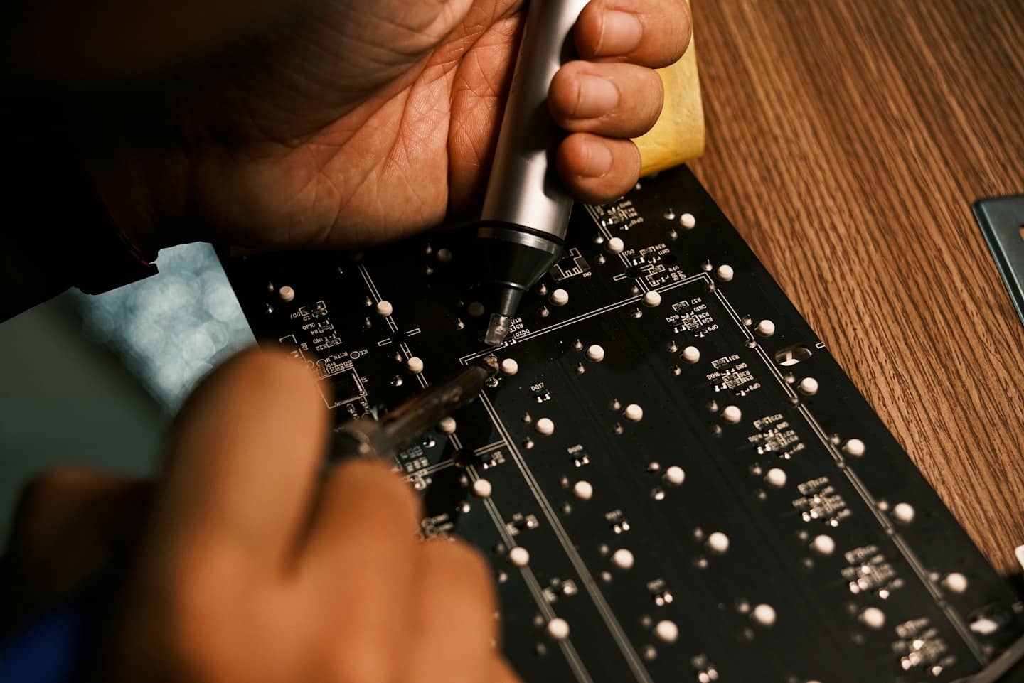 Technician uses soldering tools to repair a circuit board.