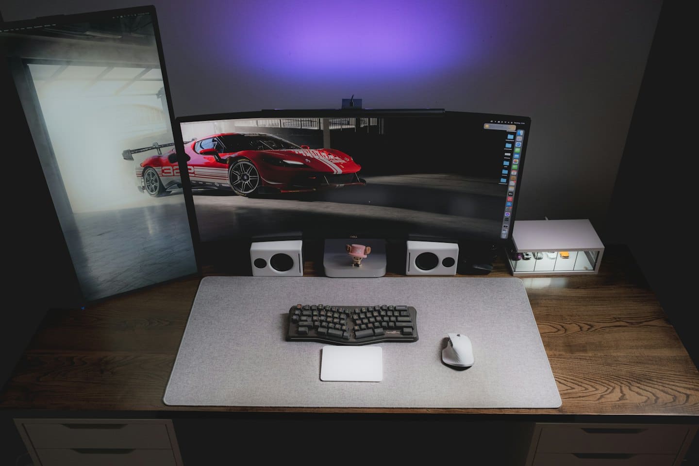 Computer desk with monitors displaying a red sports car.