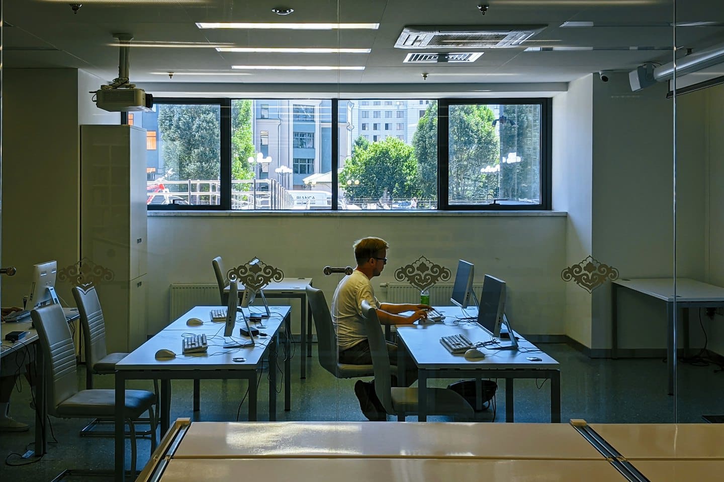 Man wearing a white t-shirt working at a desktop computer.